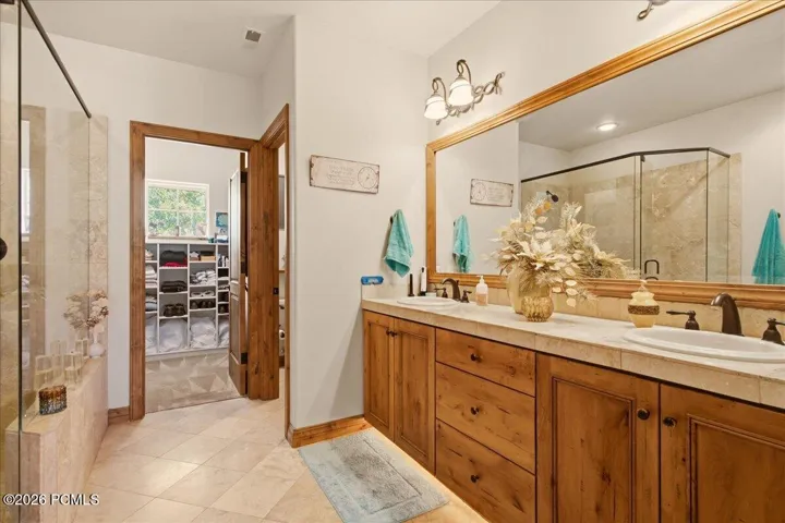 Owner's Bathroom featuring a dual vanity with wood-finish cabinetry, a large framed mirror, and integrated lighting