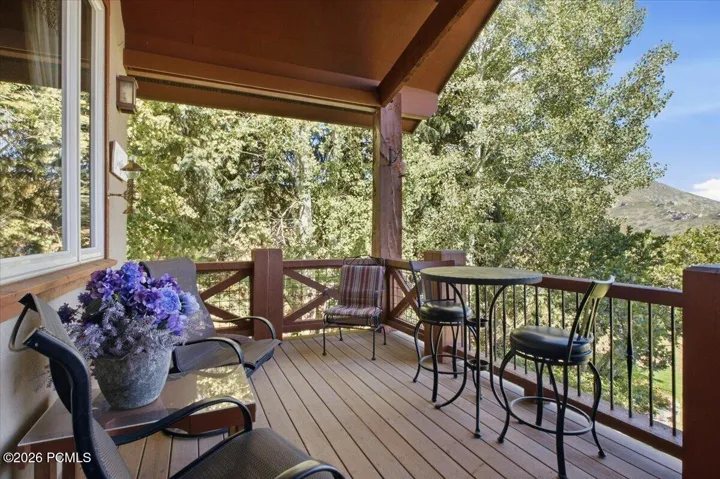 Spacious outdoor deck with wood-finish flooring, wood railings, and a mountain backdrop