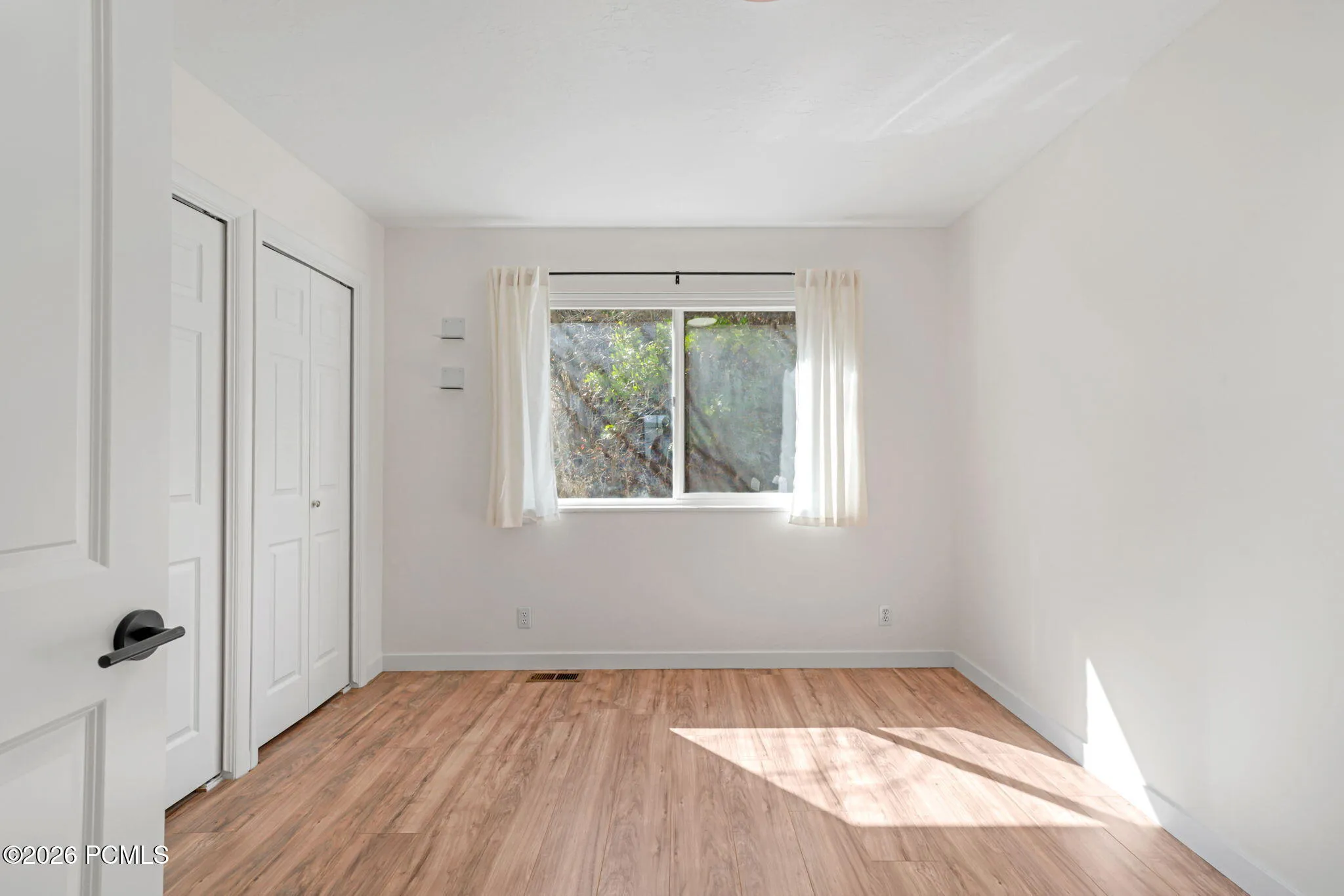 Wood-finish flooring, white walls, and a window with natural light