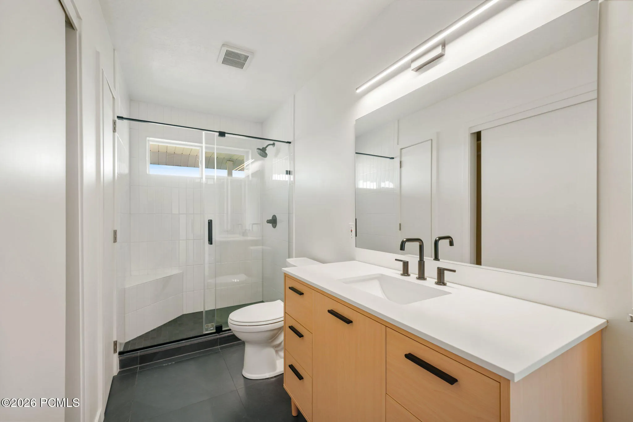 Master Bathroom: Glass-enclosed shower with a built-in bench, black-finish fixtures, and a window