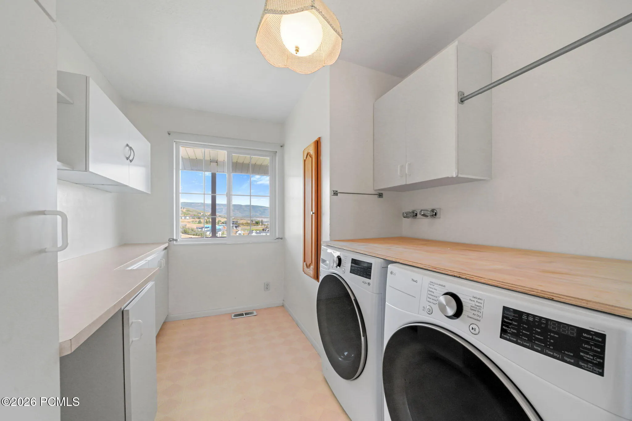 Utility room with light-colored flooring, white cabinetry, and a wood-finish countertop
