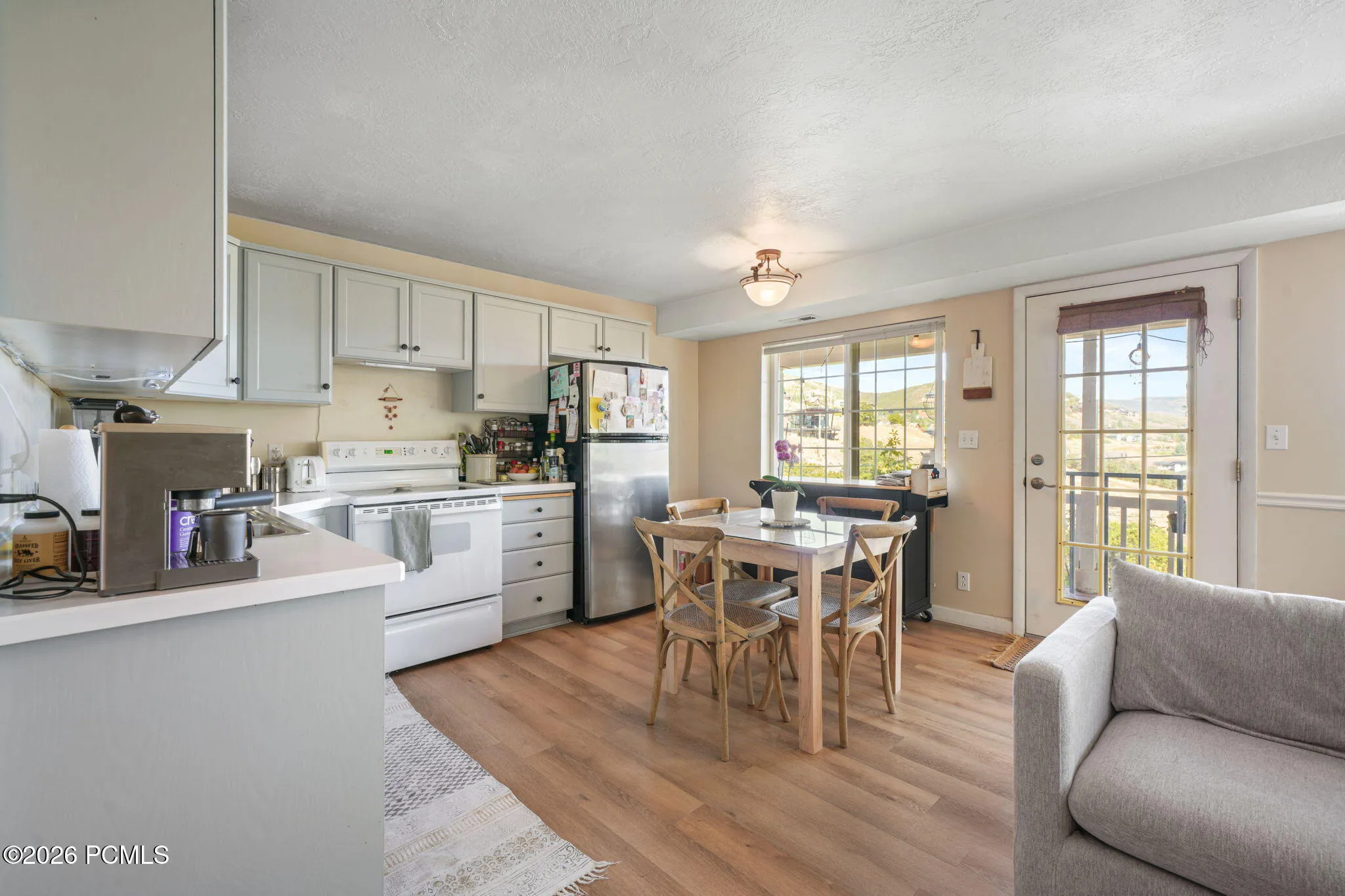 Kitchen with wood-finish flooring, light-toned cabinetry, and stainless steel appliances