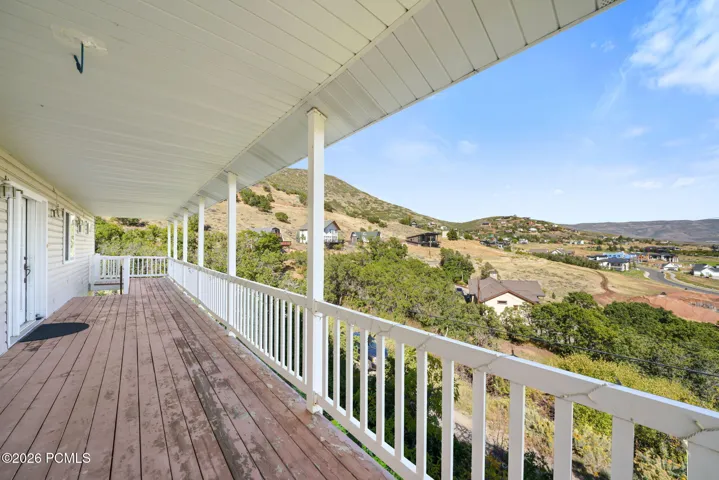 Expansive outdoor deck featuring wood-finish flooring and a white railing system