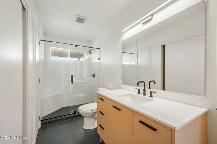 Master Bathroom: Glass-enclosed shower with a built-in bench, black-finish fixtures, and a window