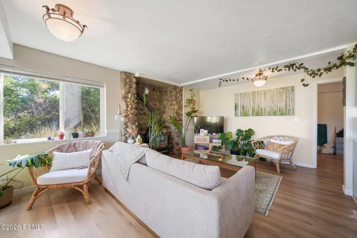 Light wood-finish flooring, stone-clad fireplace, white window trim, and semi-flush mount lighting fixtures
