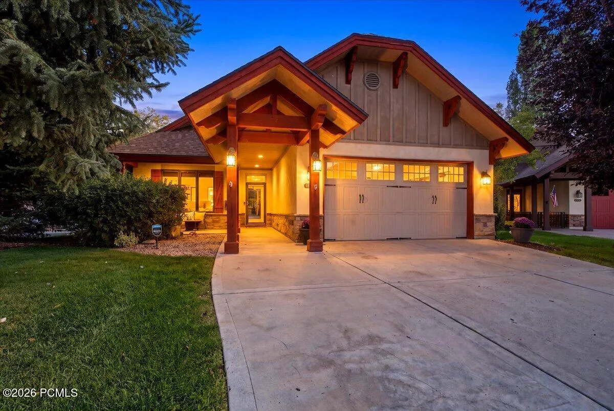 Front of home featuring an attached two-car garage, spacious concrete driveway, and mature landscaping