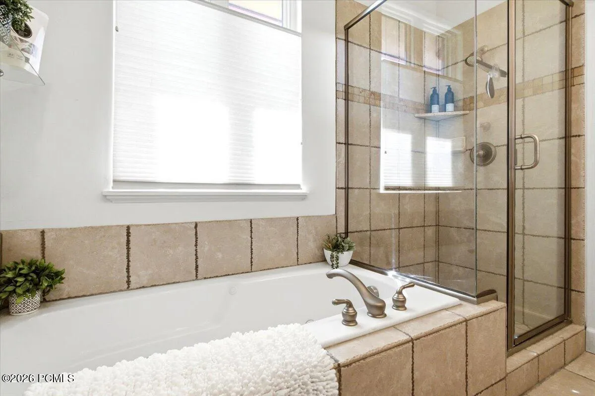Primary suite bathroom featuring a bathtub and shower