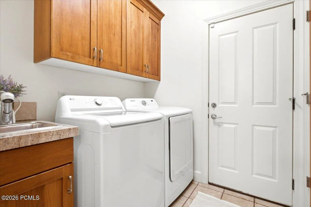 Laundry area featuring wood cabinetry, a built-in sink with a countertop, and extra storage