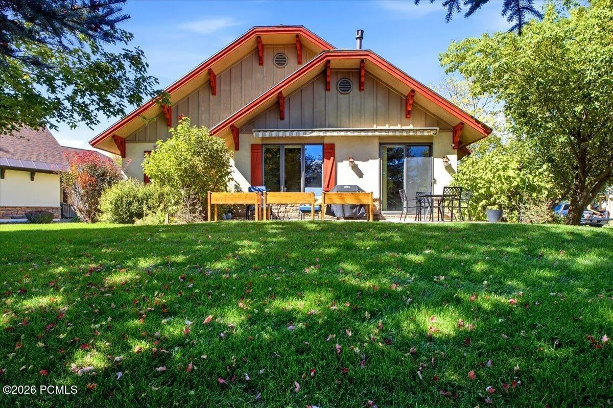 Rear of home featuring an expansive lawn with mature trees