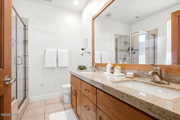 Primary suite bathroom featuring a dual vanity with granite countertops