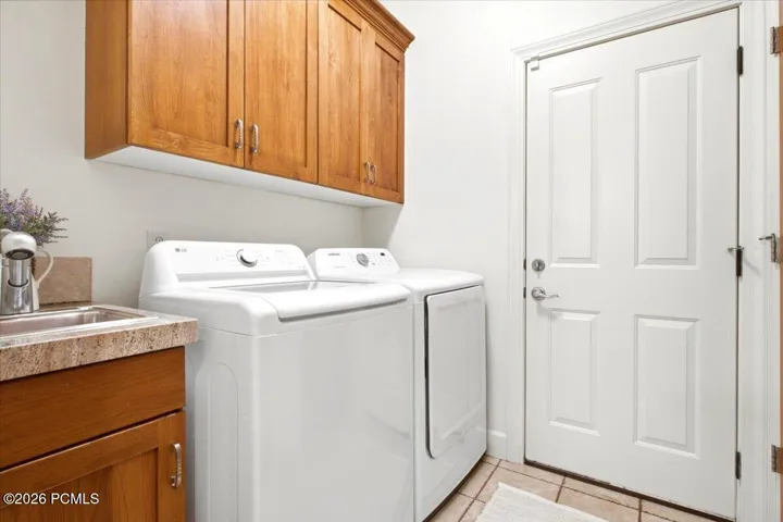 Laundry area featuring wood cabinetry, a built-in sink with a countertop, and extra storage