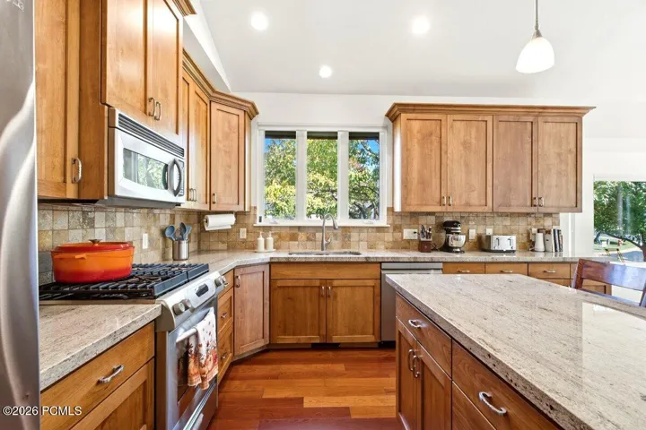 Kitchen featuring warm wood cabinetry, granite countertops, and hardwood flooring