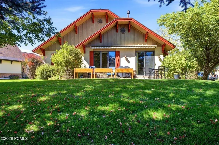 Rear of home featuring an expansive lawn with mature trees