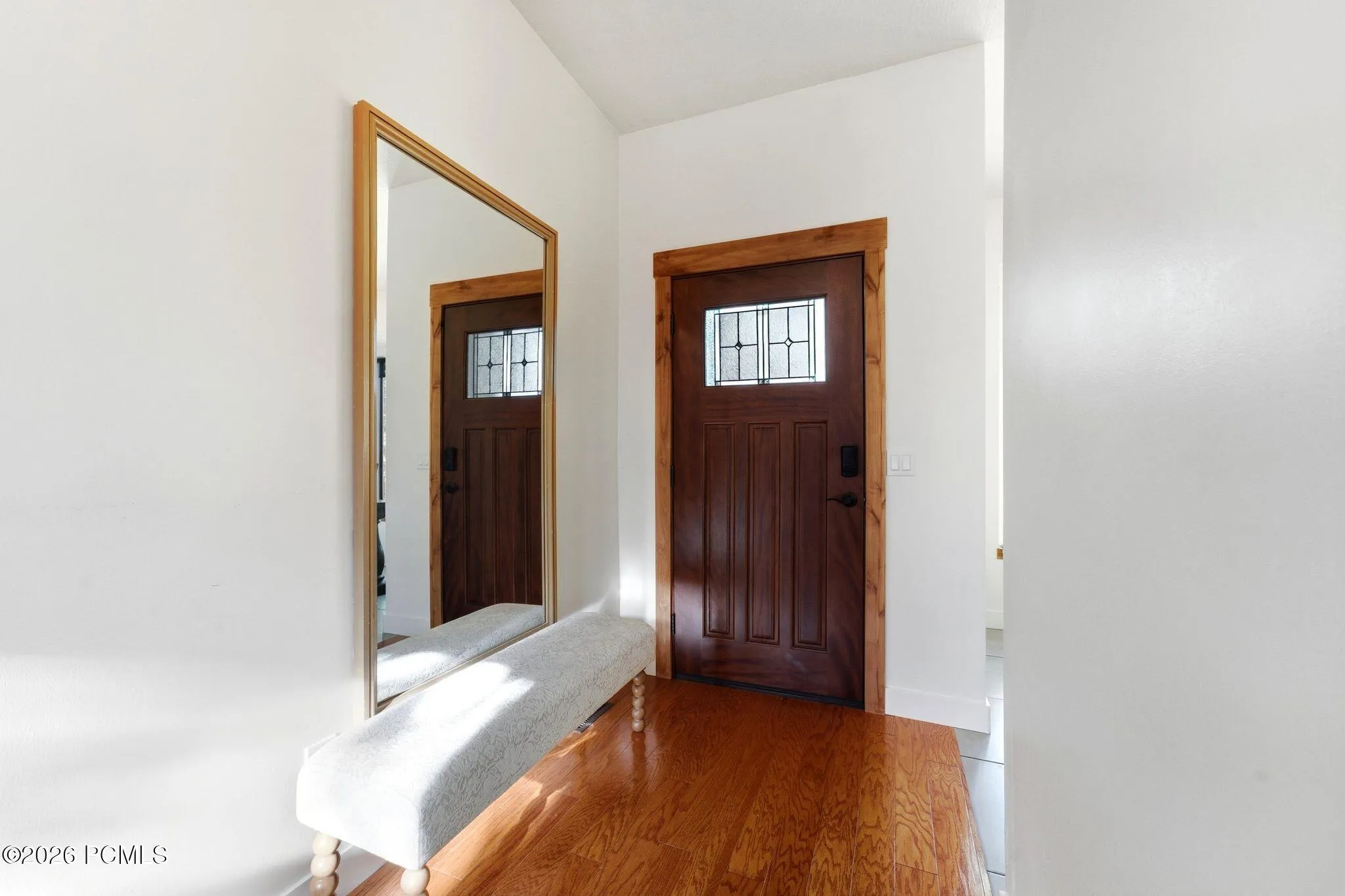 A wood front door with a leaded-glass window opens into a vaulted entry.