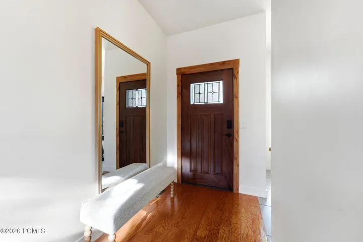 A wood front door with a leaded-glass window opens into a vaulted entry.