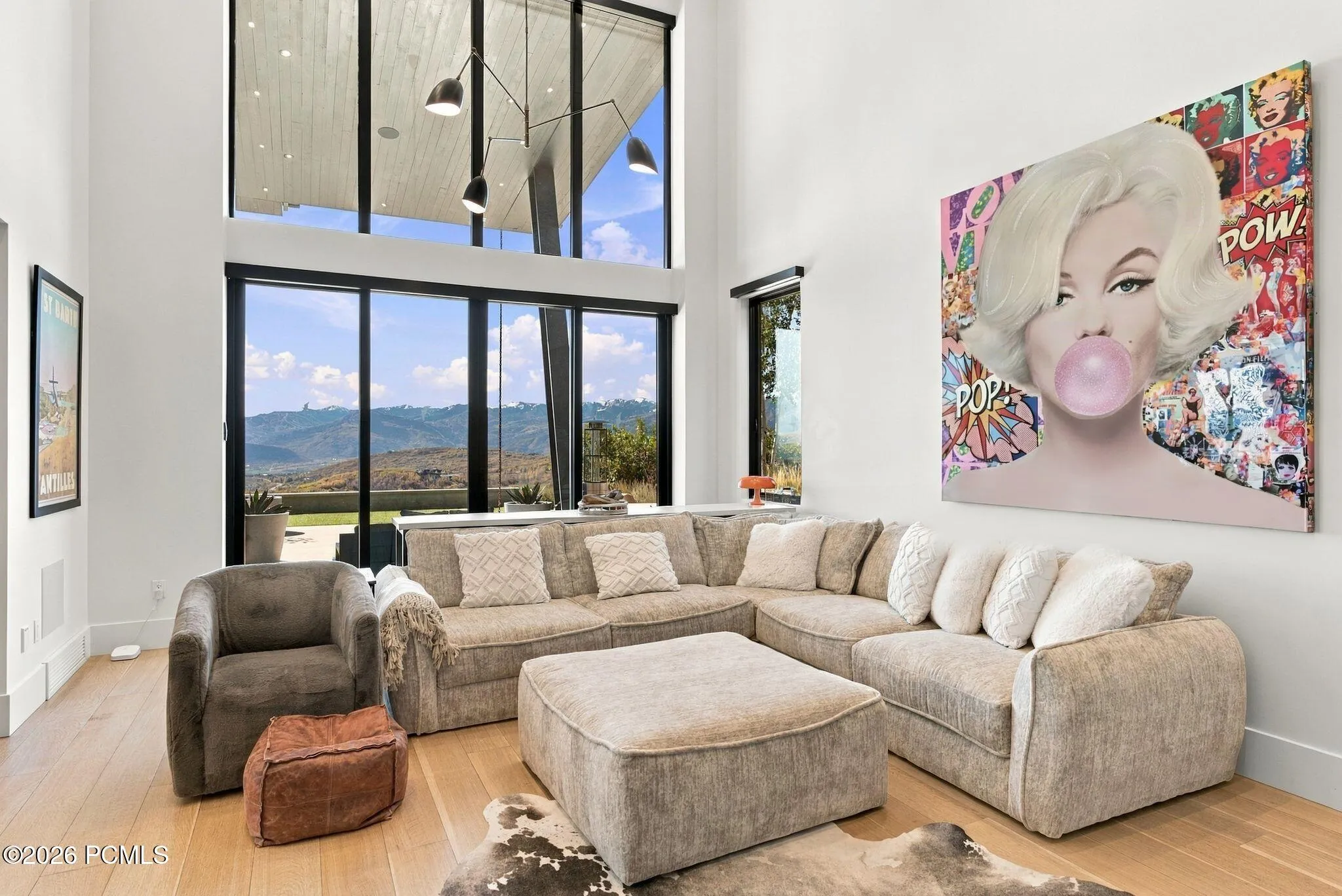 Den/media room with vaulted ceilings, floor-to-ceiling windows feautring mountain views, wood-finish flooring, accent wall, and built-in cabinetry