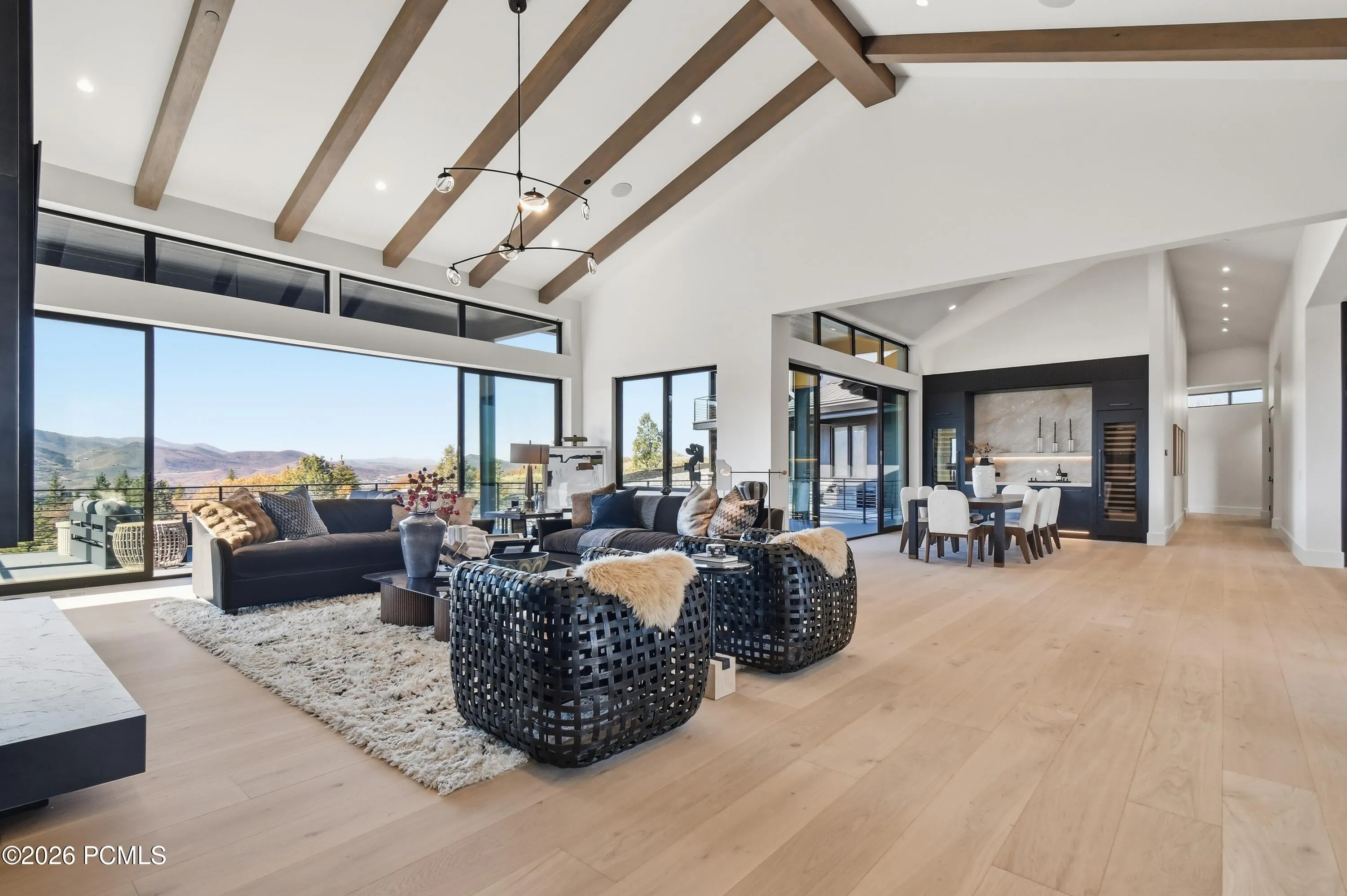 The living, dining & kitchen spaces unfold within the spectacular great room, where uninterrupted sightlines & effortless transitions create a remarkable sense of openness. Soaring vaulted ceilings adorned with richly textured wood beams, European white oak flooring & a commanding floor-to-ceiling metal fireplace establish a sophisticated balance of warmth & contemporary refinement, while a magnificent gallery of glass frames sweeping Deer Valley vistas throughout the interconnected spaces.