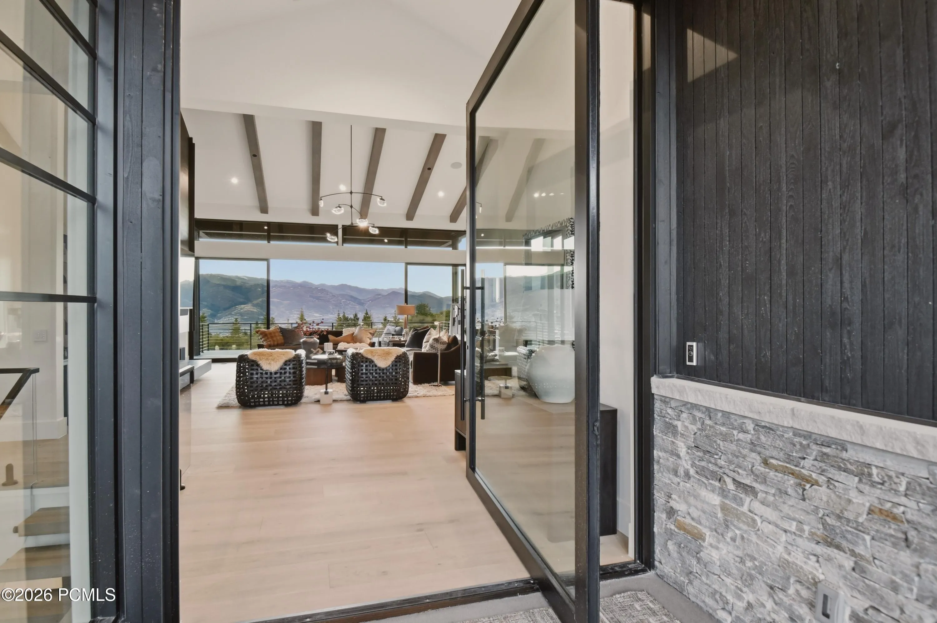 The grand glass pivot door creates a captivating introduction to this private mountain sanctuary, dissolving the boundaries between refined interiors & the breathtaking alpine landscape, where the iconic peaks of Deer Valley become an extension of the living experience.