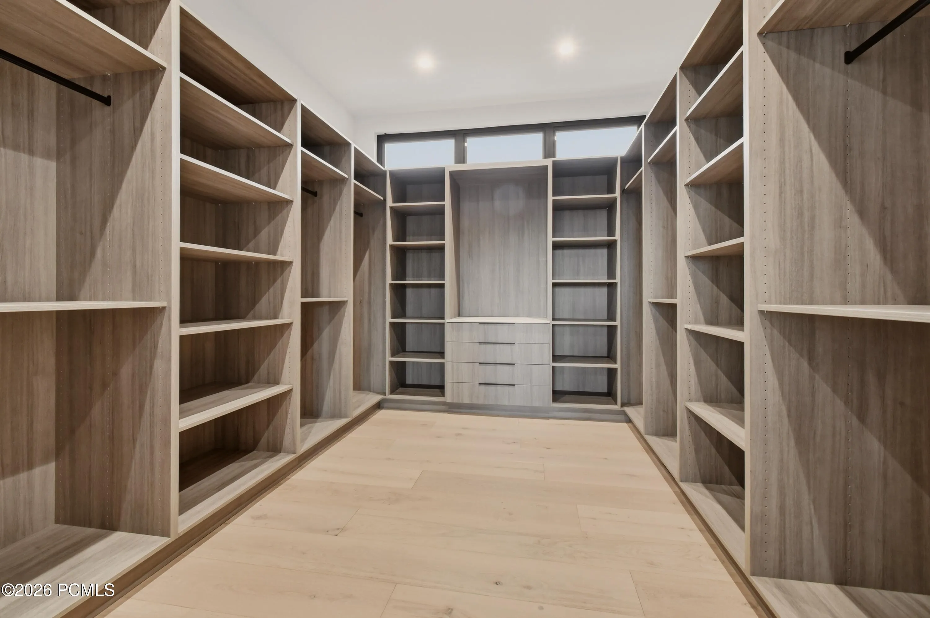 An expansive walk-in dressing room evokes the refinement of a private couture boutique, with an adaptable wardrobe system featuring adjustable hanging sections & shelving. Designed to accommodate an exceptional collection of designer apparel, accessories & seasonal wardrobes, every element can be tailored to reflect your personal style & organizational preferences.
