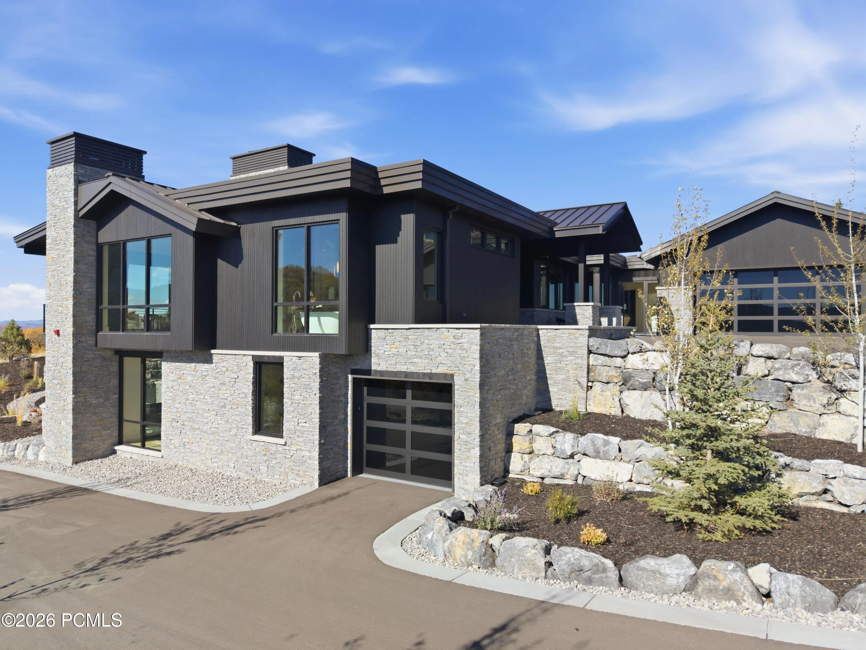A compelling expression of mountain modern design, the exterior balances clean architectural lines with a restrained palette of materials. A distinctive glass garage door introduces an unexpected element of transparency & contemporary character, elevating the façade with a refined detail that speaks to the home’s carefully curated aesthetic.