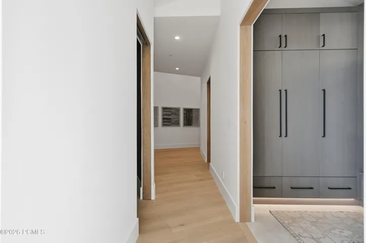 An artful departure from conventional corridor design, this elegantly tapered hallway gradually broadens, creating a distinctive sense of openness & architectural dimension. Precision crafted kerfed door & window openings eliminate traditional trim, lending a sculptural clarity that accentuates their proportions. These understated yet meticulously executed details reflect the exceptional craftsmanship woven throughout the home.