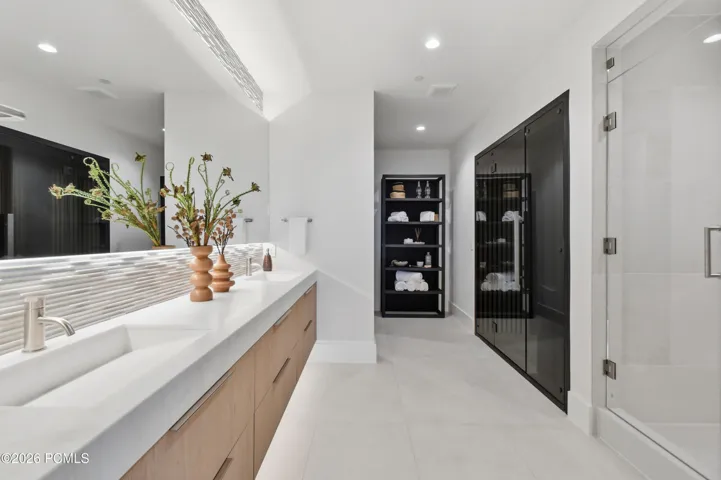 Beyond the rhythm of the home’s gathering spaces lies a dedicated wellness wing, an exclusive domain where restorative rituals become part of everyday living. The experience begins in an opulent spa-inspired bath, where an elegant dual-sink vanity sets the tone for a more indulgent approach to personal care. Step into the enveloping warmth of a steam shower or surrender to the soothing heat of a dedicated sauna, each inviting a moment of stillness & renewal. A distinguished wellness destination conceived for those who value the privilege of restoration within their own home & time.