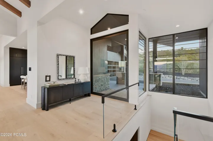 A captivating interplay of light, glass & sculptural form defines the extraordinary entry, where expansive walls of windows immerse the space in natural light & a dramatic floating staircase with glass detailing appears suspended within the surrounding alpine panorama. A masterful balance of light, transparency & understated sophistication creates an enduring first impression.