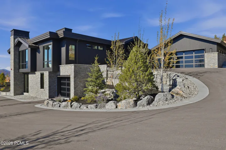 A generously scaled driveway sets the stage for a distinguished arrival, its sweeping expanse framed by meticulously defined curbing that brings tailored precision to the approach. The crisp edges & carefully finished contours lend the grounds a polished, estate-worthy presence, creating an impressive introduction to the home’s mountain-modern architecture.