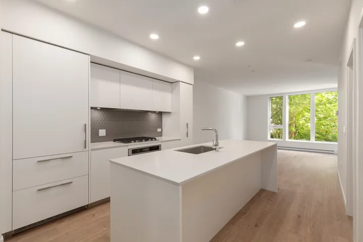 Contemporary kitchen featuring flat-panel cabinetry, a large kitchen island with an undermount sink and gooseneck faucet, a built-in cooktop with a honeycomb tile backsplash, and recessed ceiling lighting