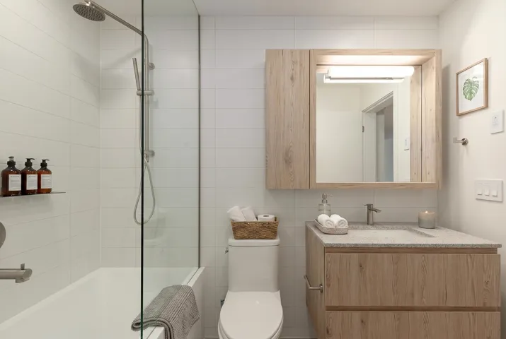 Contemporary bathroom featuring a light wood-finish vanity with an integrated sink and light-toned countertop