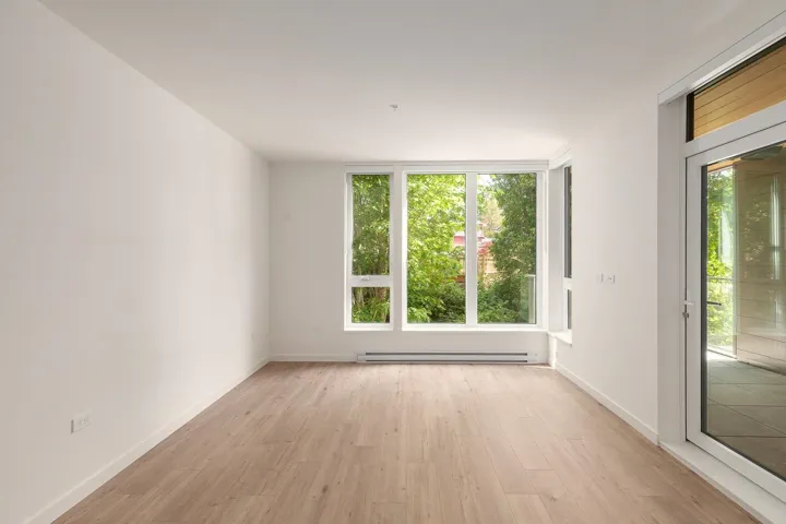 Bright interior space featuring a multi-pane window configuration, wood-finish flooring, white baseboards, and a glass-paneled door