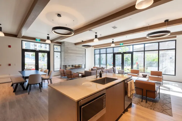 Spacious common area featuring wood-finish flooring, exposed ceiling beams, and contemporary pendant lighting