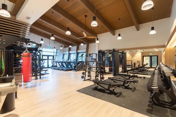 Spacious fitness center featuring vaulted wood-paneled ceilings, exposed wood beams, and recessed lighting