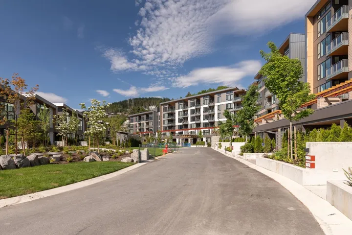 Modern multi-story buildings featuring balconies, expansive window panels, and a concrete and wood-panel exterior