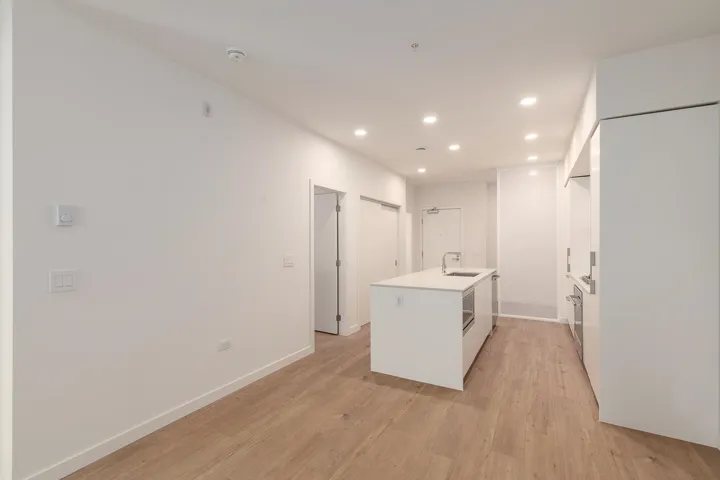 Contemporary kitchen featuring a center island with integrated sink, stainless steel under-counter microwave, and sleek white cabinetry
