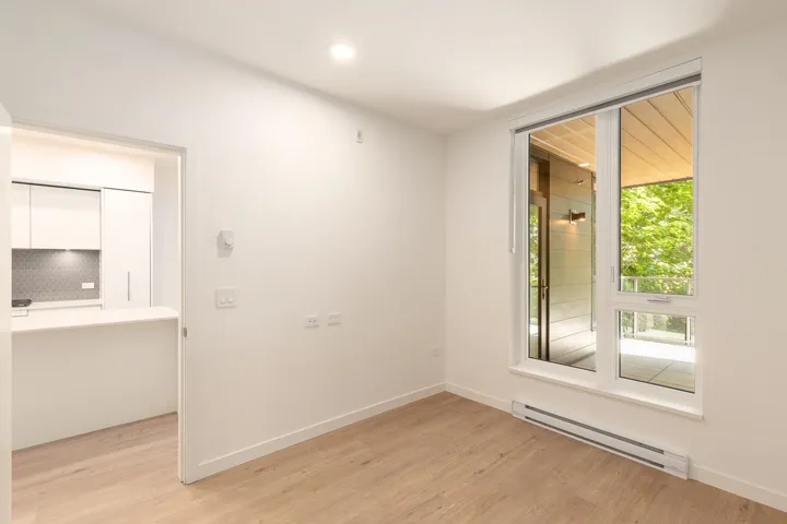 Bright living area featuring wood-finish flooring, white walls, and a large window with a transom