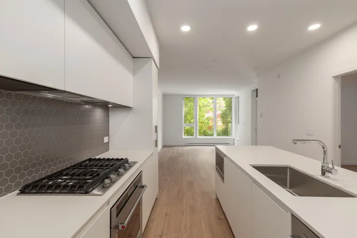 Contemporary kitchen featuring white cabinetry, a gas cooktop with an integrated oven, a hexagonal tile backsplash, a kitchen island with an undermount sink, and recessed lighting