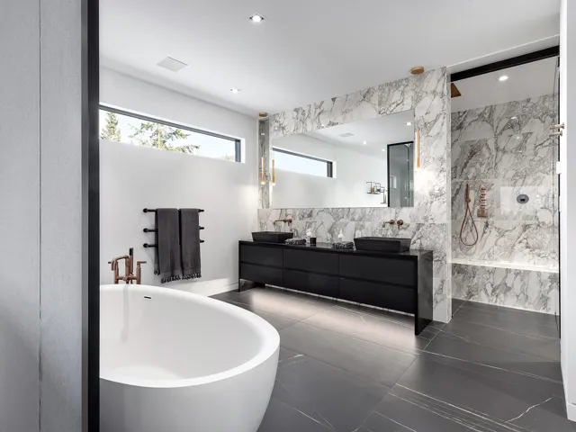 Full bath featuring tile walls, a marble finish shower, double vanity, a freestanding tub, and dark tile patterned flooring