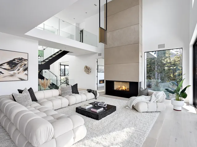 Living area with wood finished floors, a tile fireplace, stairs, and a towering ceiling