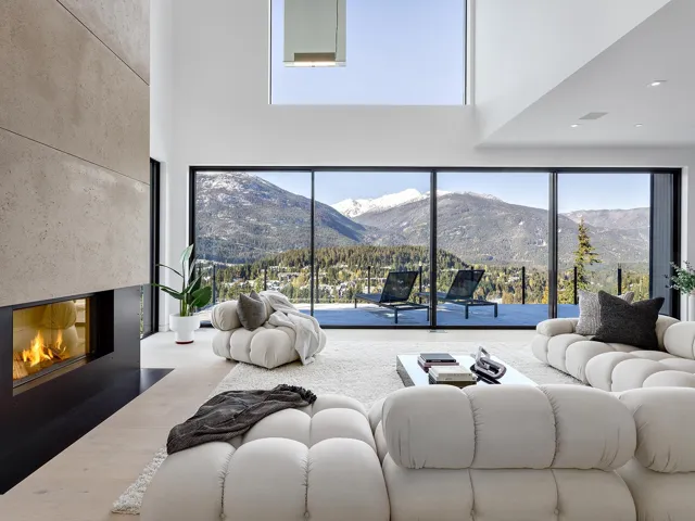 Living area featuring wood finished floors, a fireplace with flush hearth, a mountain view, and a towering ceiling