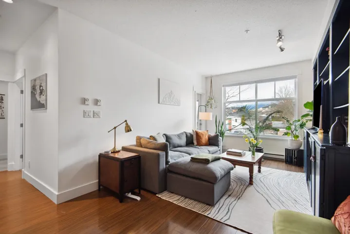 Living room with baseboards, baseboard heating, wood finished floors, and a textured ceiling