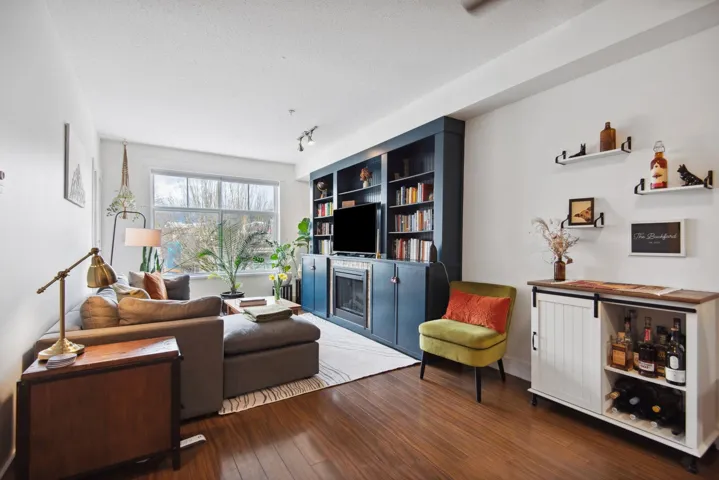 Living room featuring built in shelves, a textured ceiling, dark wood-style floors, and a fireplace