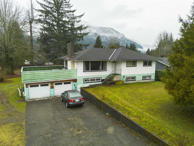 View of front of property with driveway, a front lawn, a mountain view, and a chimney
