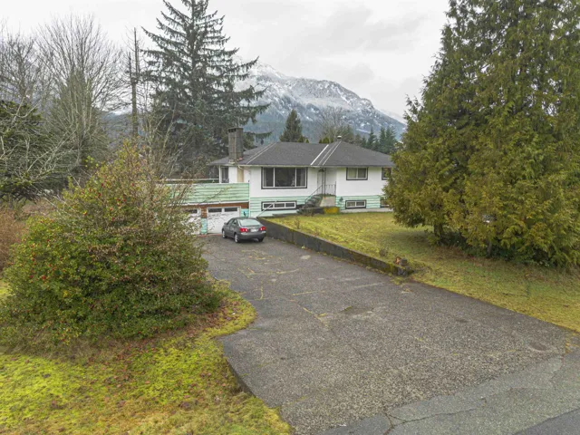 View of front facade with asphalt driveway, a chimney, a front yard, and a mountain view