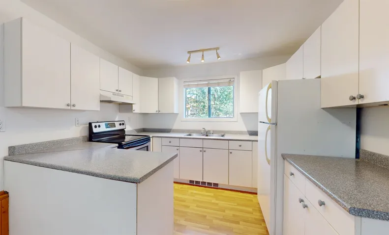 Kitchen featuring under cabinet range hood, stainless steel electric range, light wood finished floors, a peninsula, and freestanding refrigerator