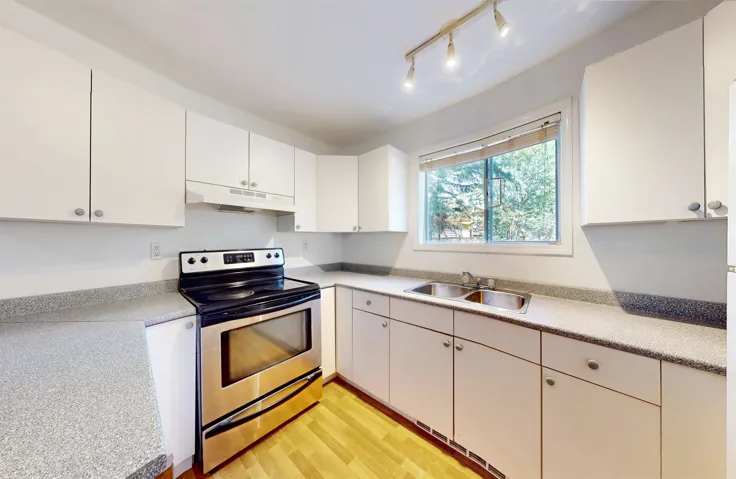 Kitchen featuring stainless steel range with electric cooktop, under cabinet range hood, light countertops, light wood finished floors, and white cabinets