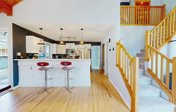 Kitchen with appliances with stainless steel finishes, light wood-type flooring, white cabinetry, a peninsula, and light countertops