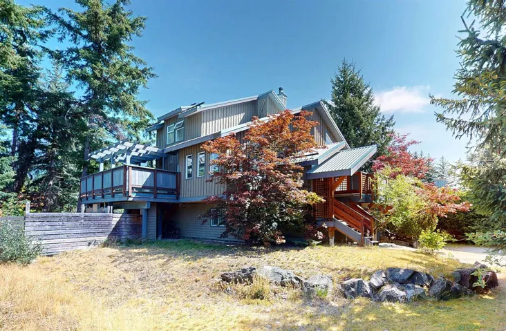 View of side of property with a deck, stairs, and a chimney