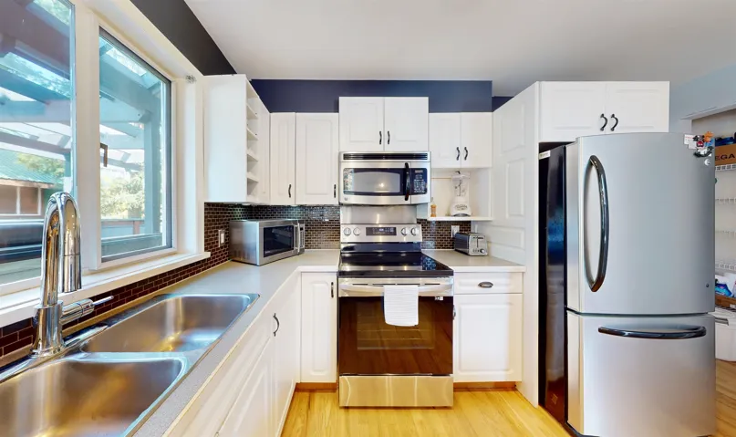 Kitchen featuring stainless steel appliances, open shelves, backsplash, white cabinetry, and light countertops