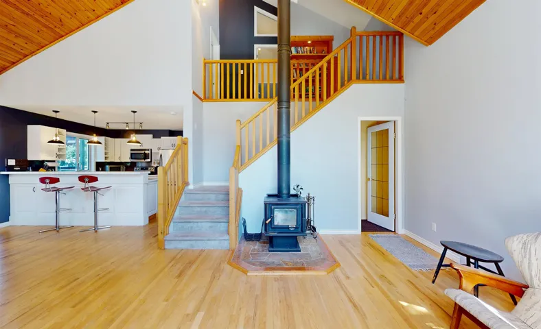 Staircase featuring wood finished floors, a wood stove, high vaulted ceiling, and wood ceiling